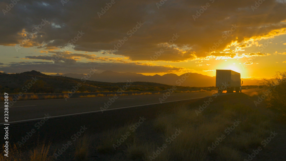 夏日日落，金色的阳光下，货运半卡车在空旷的高速公路上超速行驶