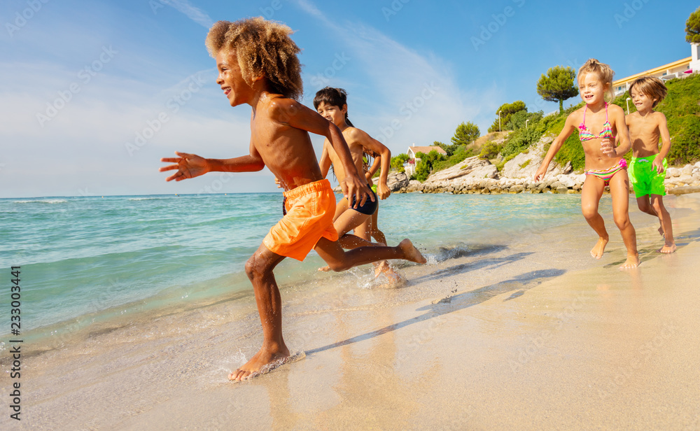 多民族孩子夏天在海滩上跑步