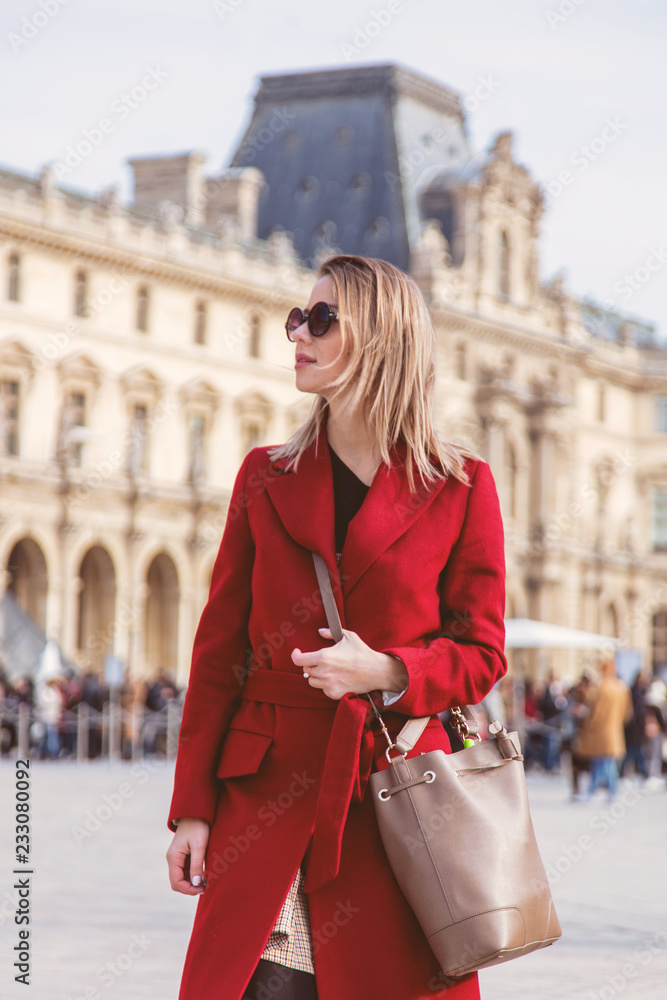 秋季巴黎街上穿着红色外套和包包的红发女孩