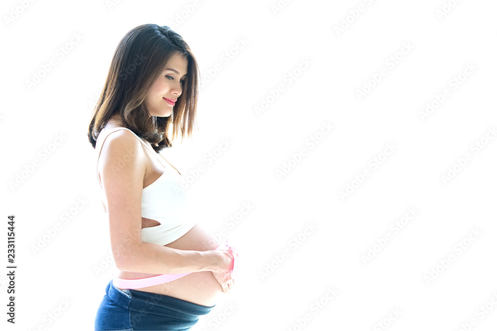 美丽微笑的亚洲孕妇侧视图，裸露的肚子上系着粉色缎带。她站着