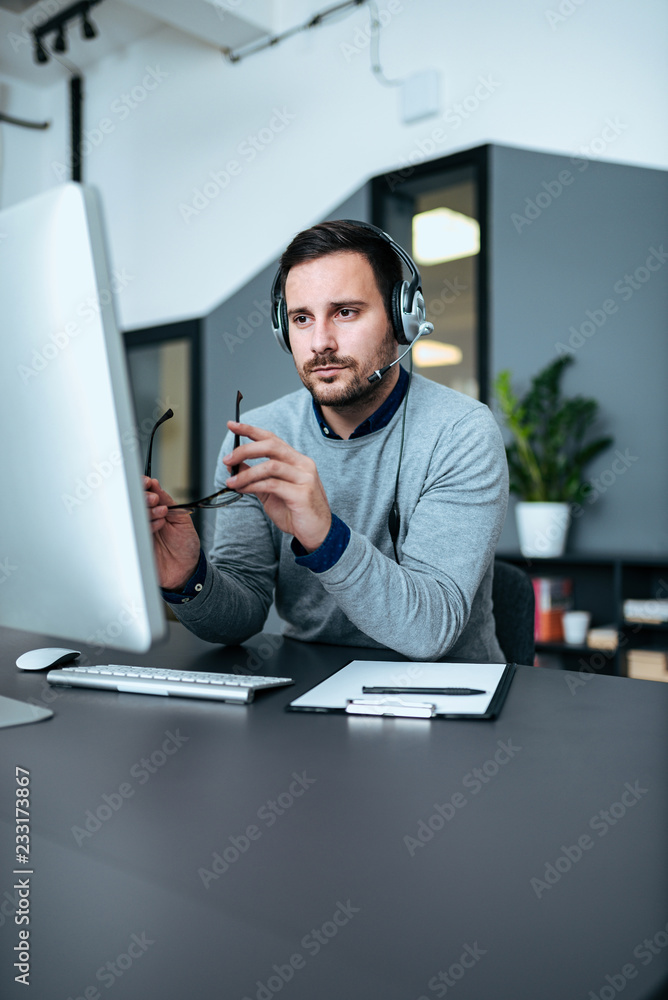 集中支持中心代理在办公室的电脑上工作，看着监视器。