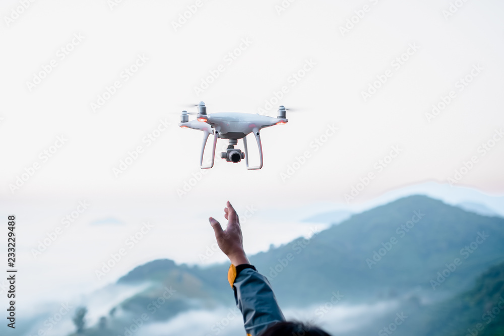 男子用无人机监控拍摄清晨的雾和山脉。手举向天空