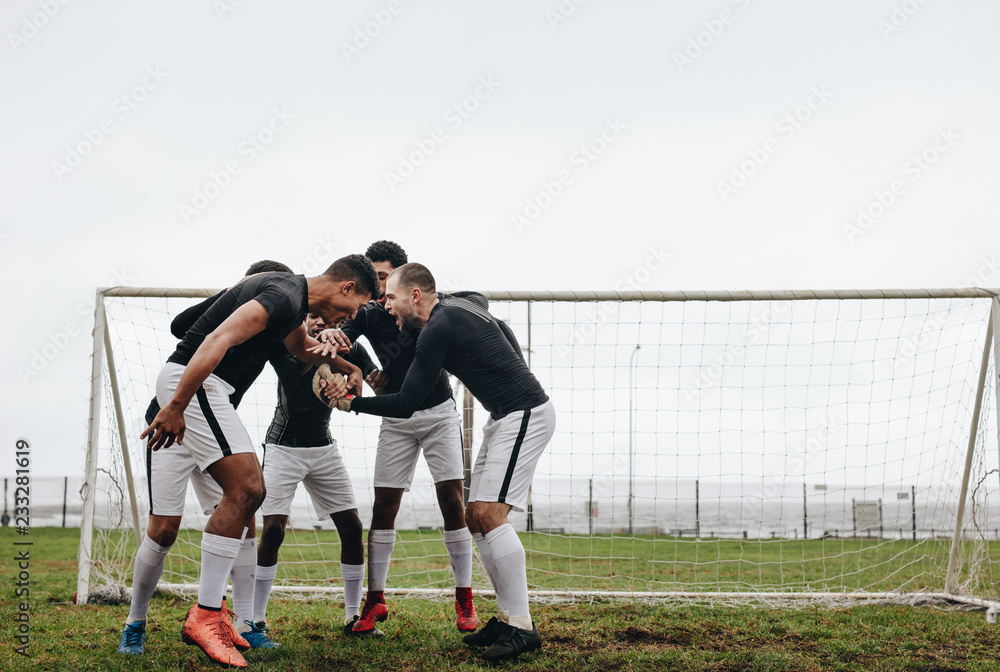 Football players standing in a huddle near goalpost