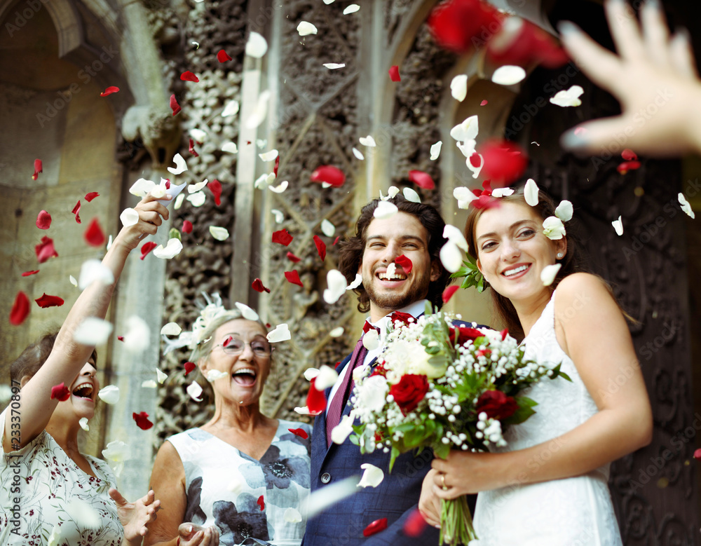 家人向新婚新娘和新郎扔玫瑰花瓣