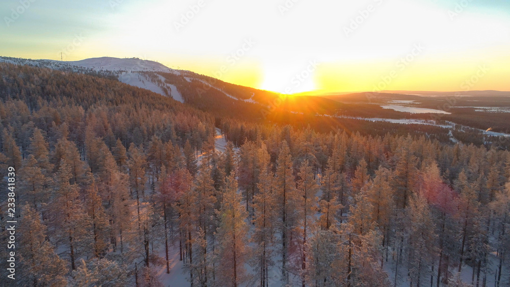 航空航天：金色的冬日阳光落在冰冻的云杉林和小型滑雪场后面