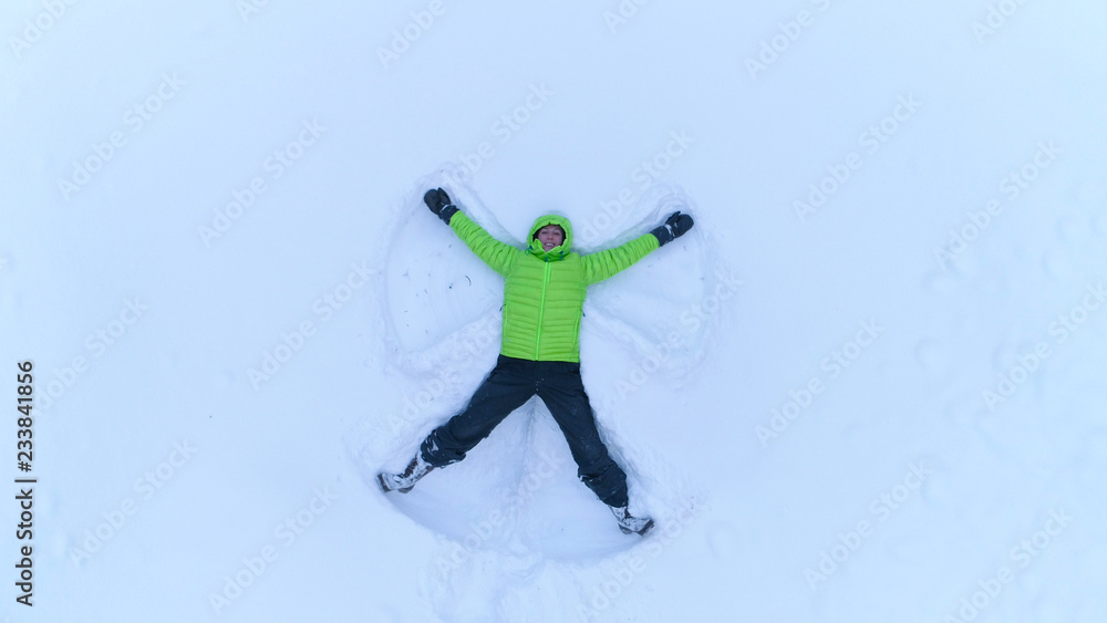 AERIAL快乐微笑的女孩在雪山上的新鲜雪中形成雪的角度