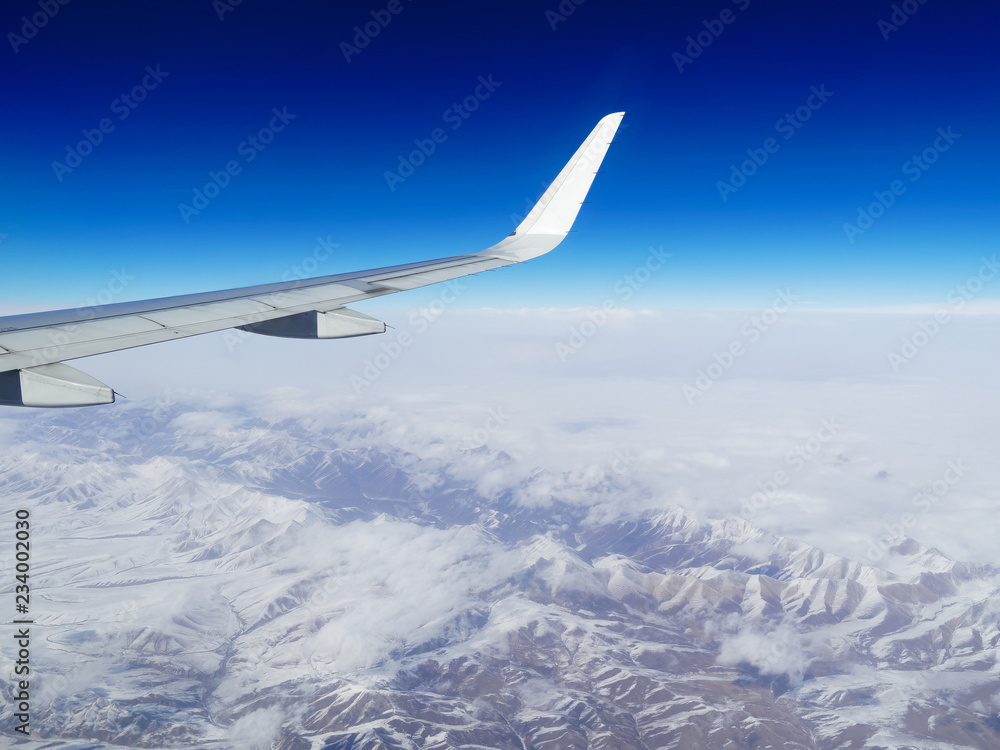 一架在中国西南部雪山上空飞行的飞机的机翼。从飞机上俯瞰