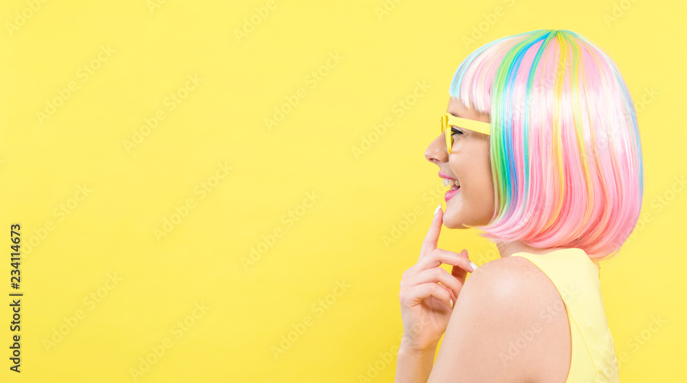戴着彩色假发，黄色背景戴着太阳镜的年轻女子