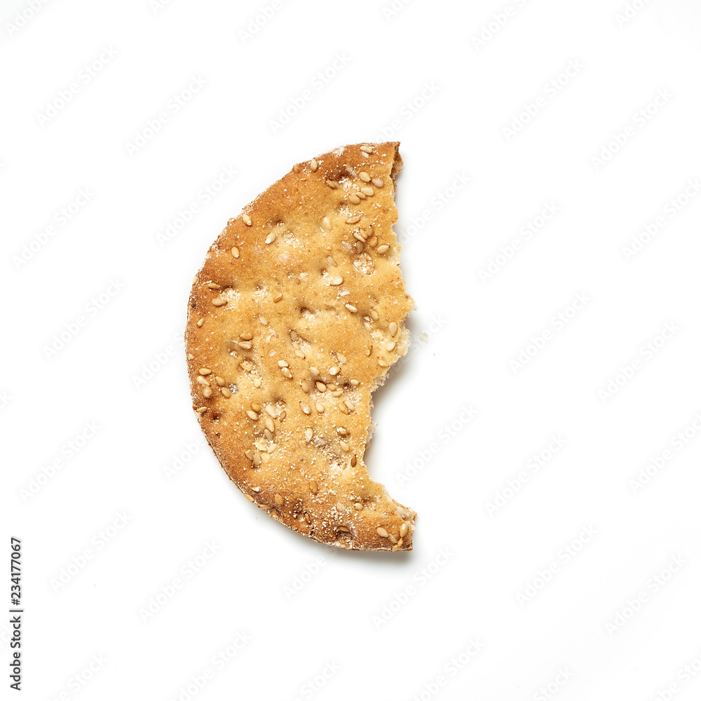 咬一口圆形的麦饼干，白底上有芝麻。