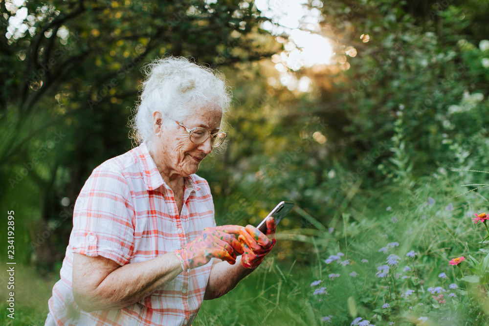 老年妇女在园艺时使用手机