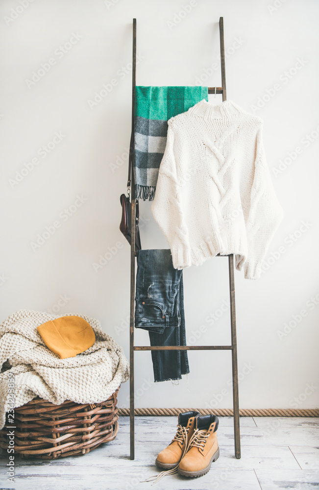 挂在衣架上的秋冬保暖针织衫，白墙背景。时尚女性套装冬季凝块