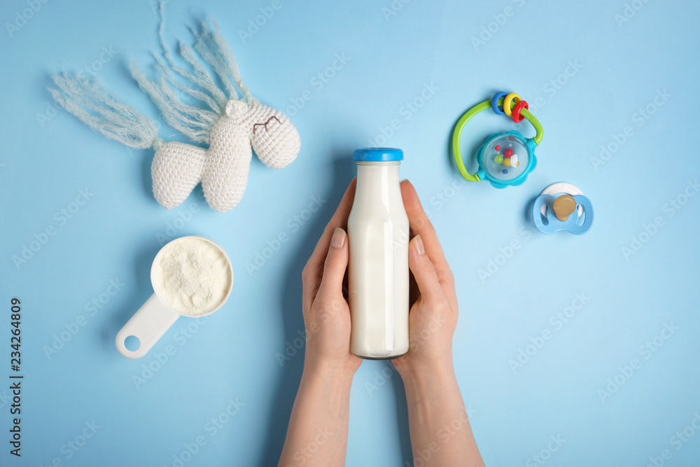 拿着一瓶牛奶的女人，背景是奶粉和玩具