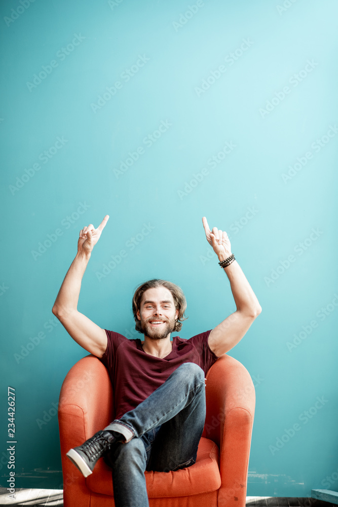 一位留着长胡子的年轻高加索男子的肖像，双手放在五颜六色的背景上