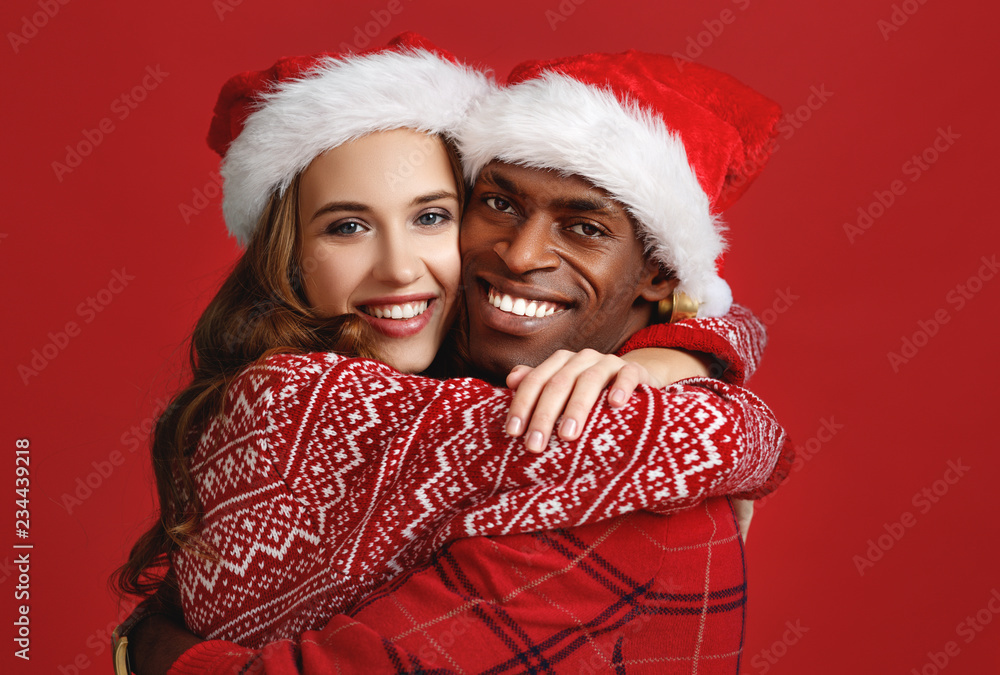 戴着红底圣诞帽的黑人男子和高加索女子幸福夫妻