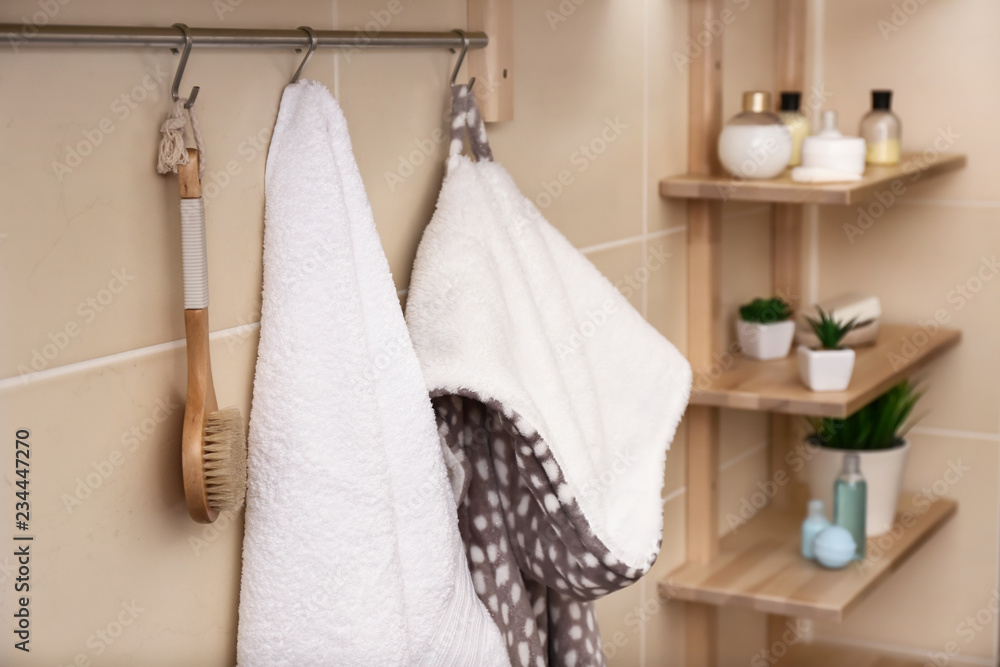 白色毛巾、刷子和浴袍挂在浴室的架子上