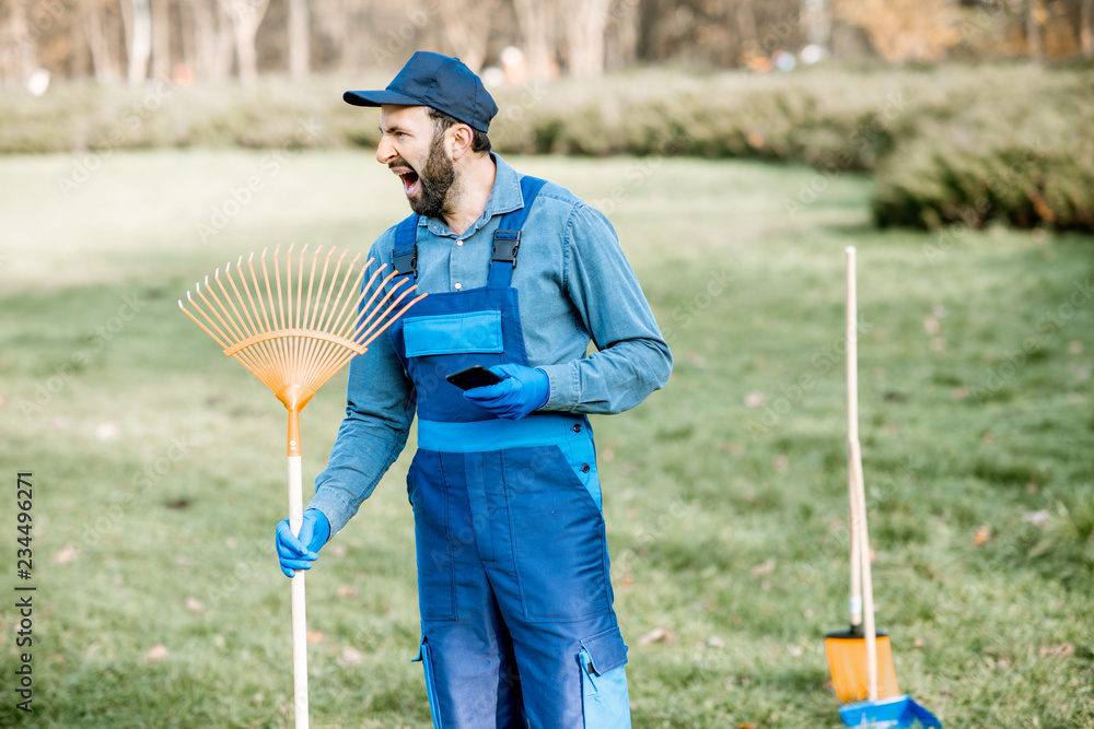 一个穿着制服的专业清洁工在花园里工作时打哈欠的有趣画像