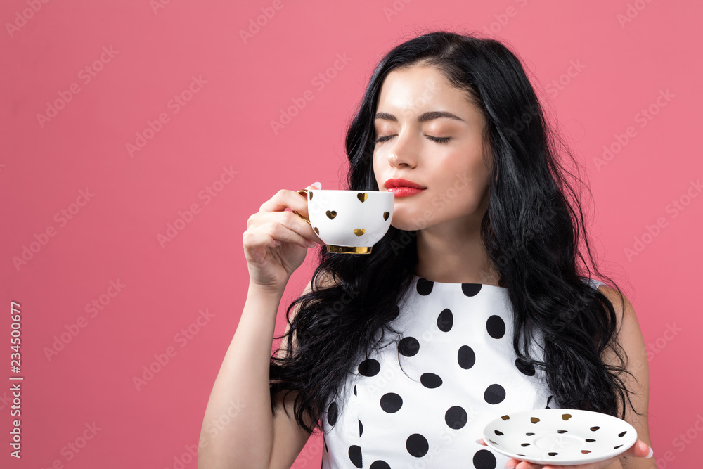 年轻女子在坚实的背景下喝咖啡