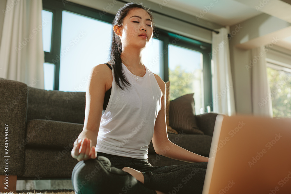 女人用笔记本电脑练习家庭瑜伽