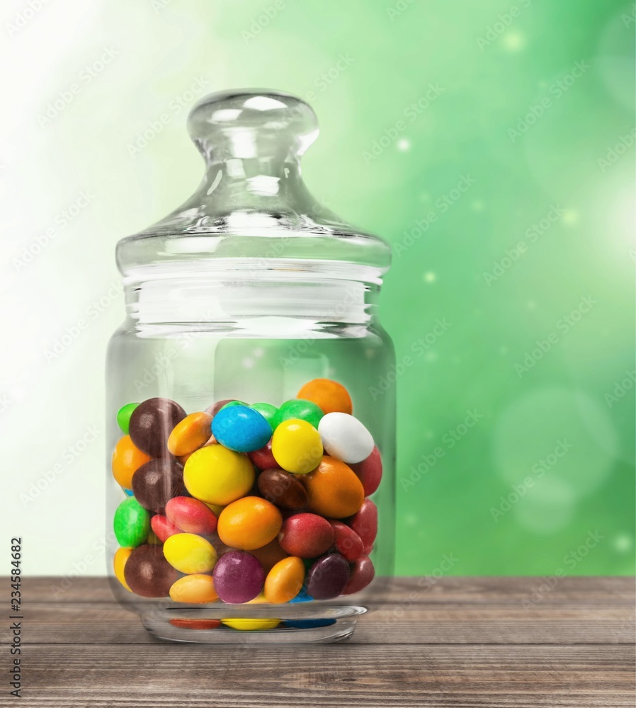 透明玻璃罐，桌上放着五颜六色的巧克力糖果