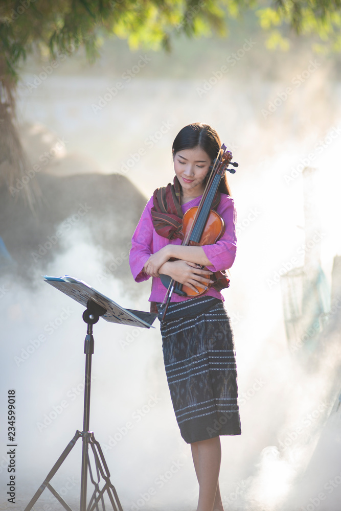 音乐、旋律、歌曲理念。亚洲美女快乐地拉着小提琴。女人喜欢演奏