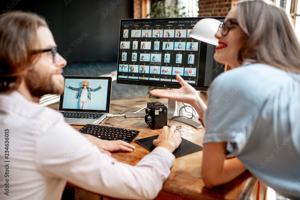 一对年轻的摄影师在工作场所用两台电脑拍摄女性肖像