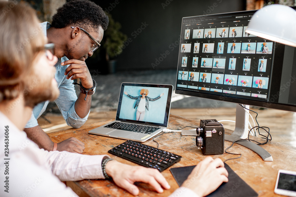 两名男性摄影师在工作室用两台电脑选择女性肖像