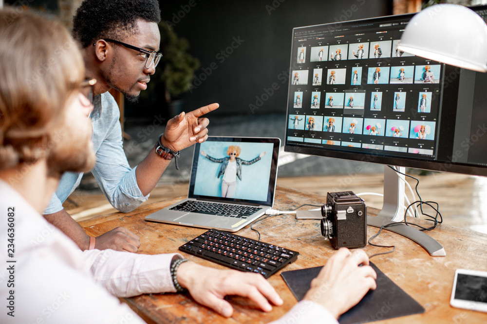 两名男性摄影师在工作室用两台电脑选择女性肖像