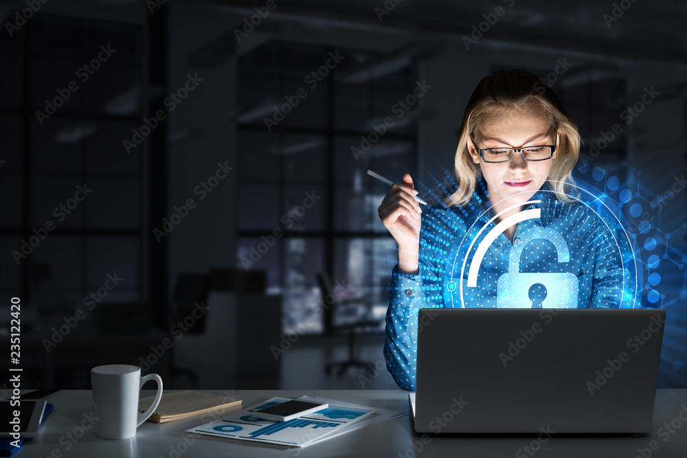 美丽的金发女郎在黑暗的办公室里用笔记本电脑工作并获得网络访问权限
