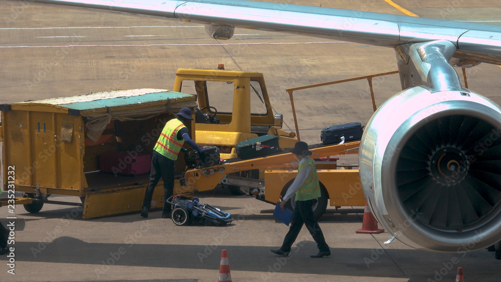 地勤人员正在收集从飞机机身出来的乘客行李。