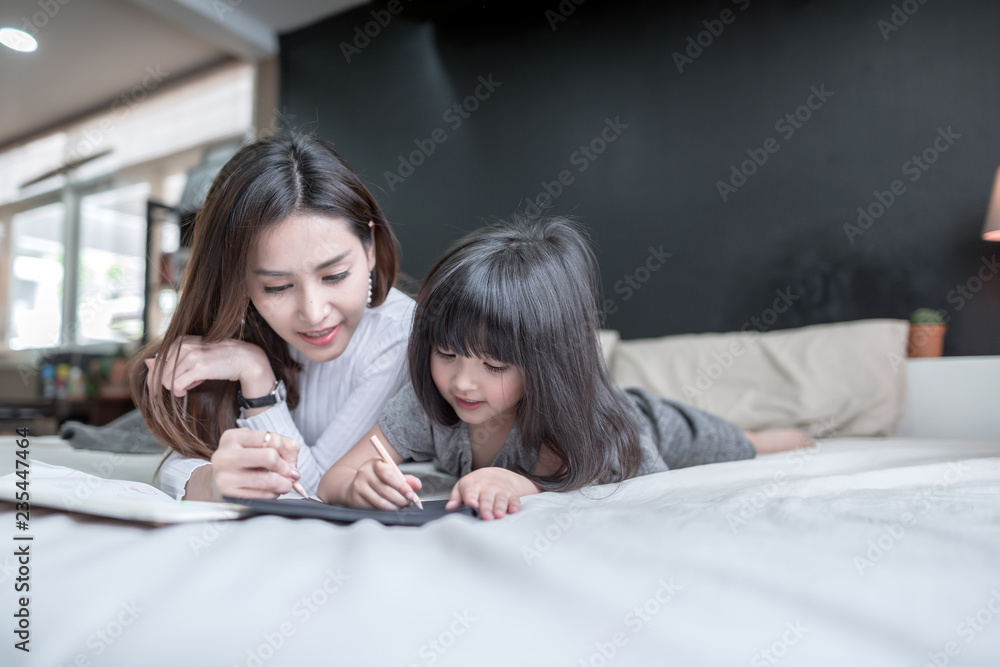 母亲和女儿在卧室里玩耍和写作的肖像
