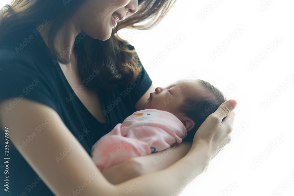美丽的亚洲微笑母亲抱着刚出生的熟睡婴儿。白色背景。她