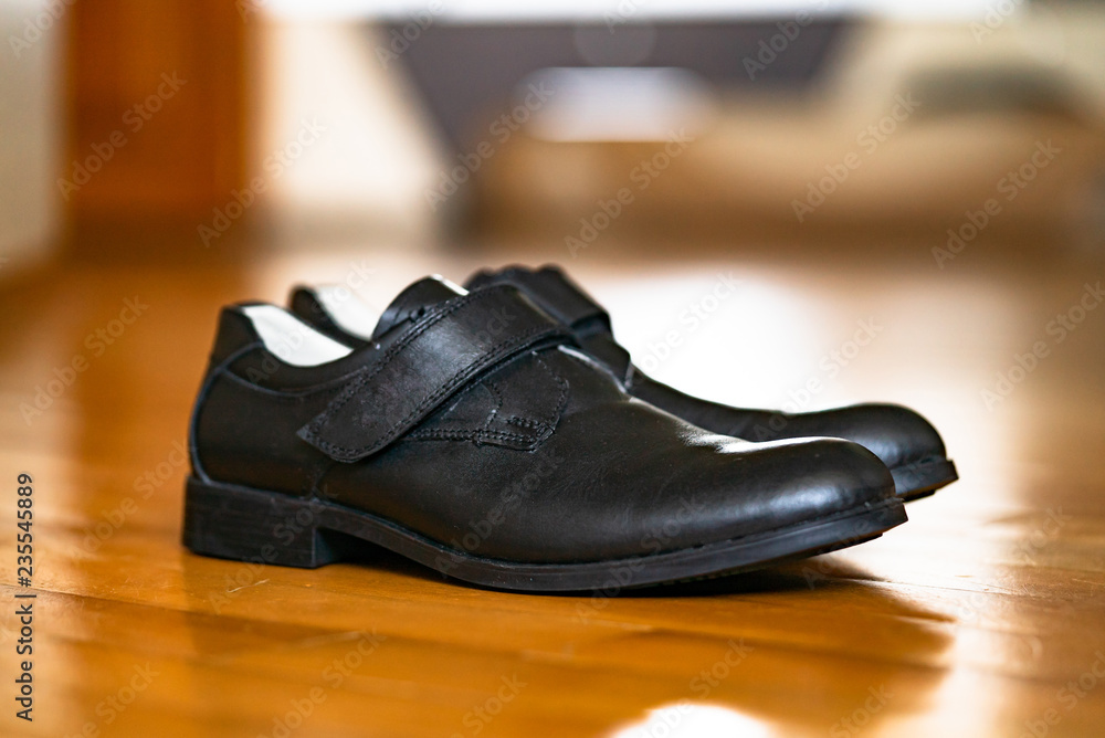 木制表面男孩穿的黑色学校鞋。现代设计，日常穿着男式黑色鞋