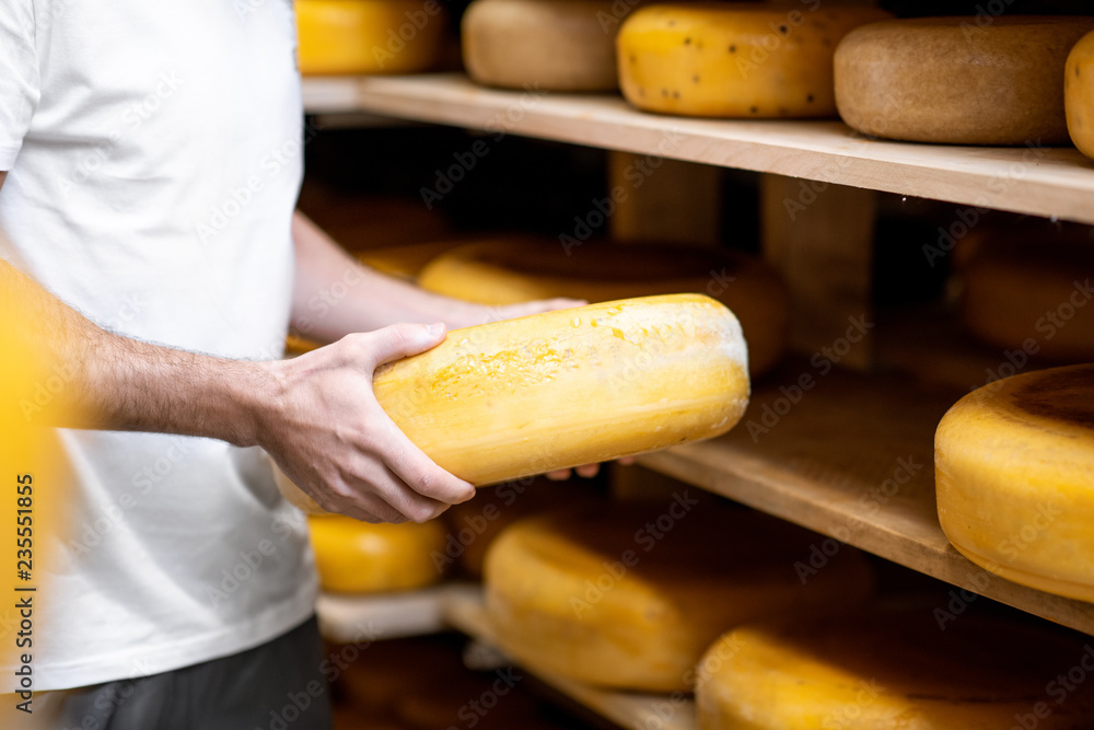 奶酪陈化过程中，工人在仓库拿奶酪轮。无fac的特写