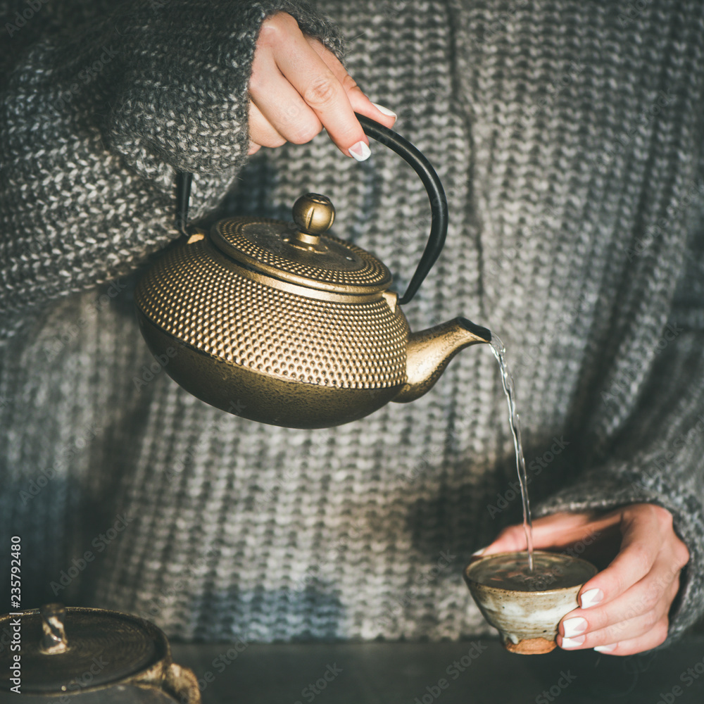女性将绿茶从壶中倒入杯中，方形作物