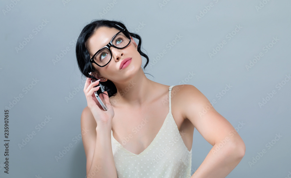 一个年轻女人在灰色背景下和她讲手机