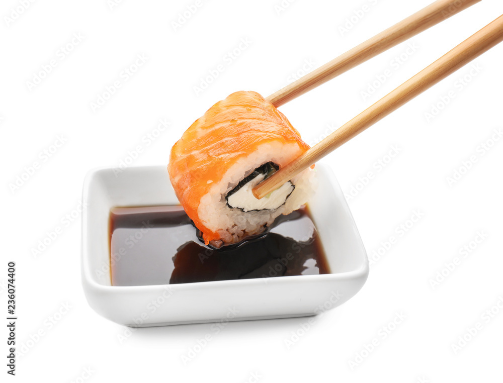 将美味的寿司卷蘸入白底酱汁碗中