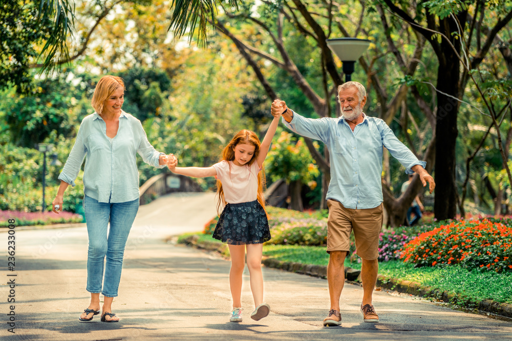 快乐健康的一家人在夏天一起走在公园的小路上。家庭纽带的概念。