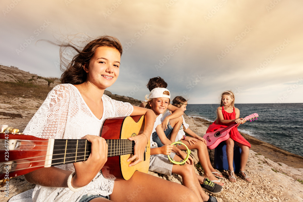 女孩和她的朋友在海滩上弹吉他