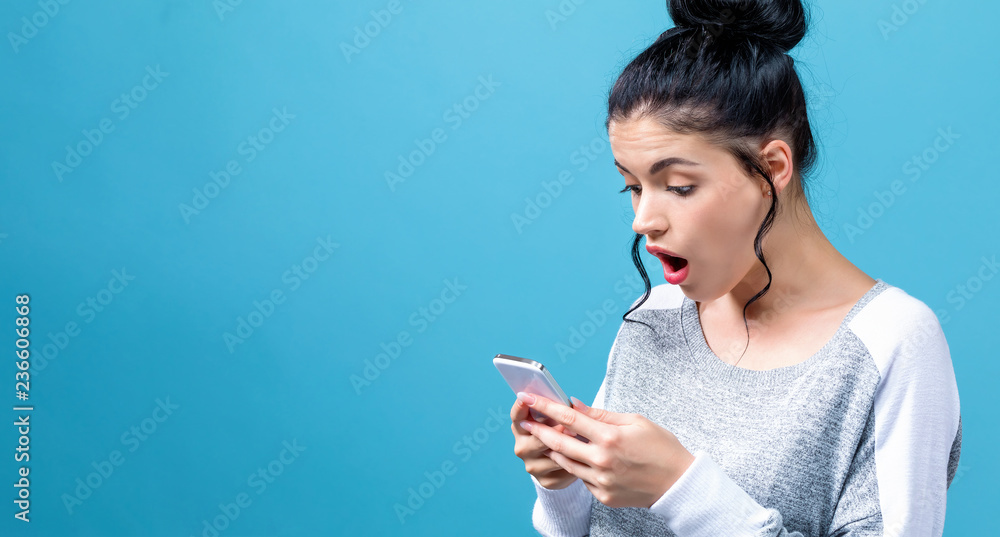 一名年轻女子在蓝色背景下盯着手机