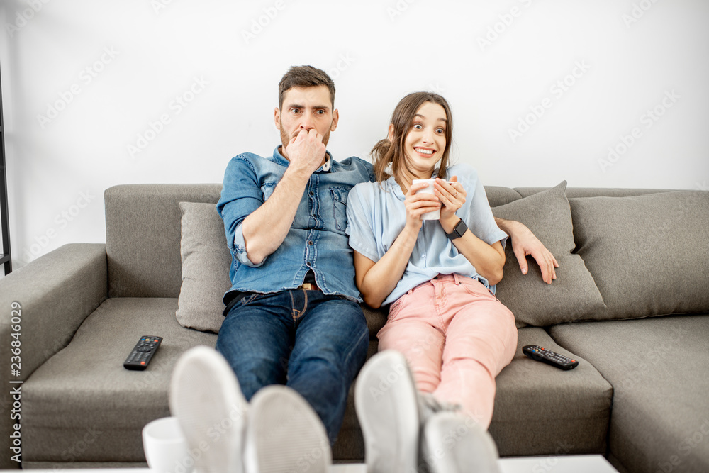 一对情绪激动的年轻夫妇坐在家里的沙发上看电视