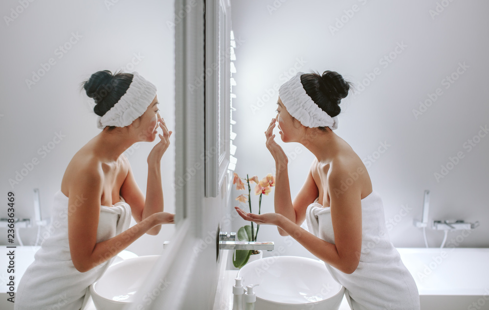 浴室里的女人在脸上涂化妆品