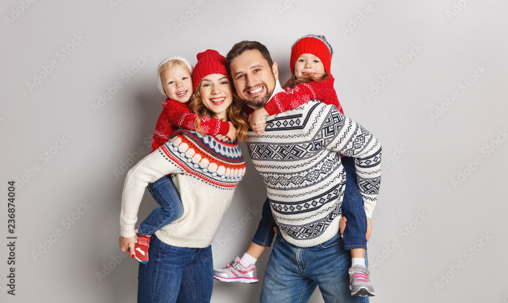 快乐的家庭母亲、父亲和孩子们戴着灰色背景的针织帽子和毛衣