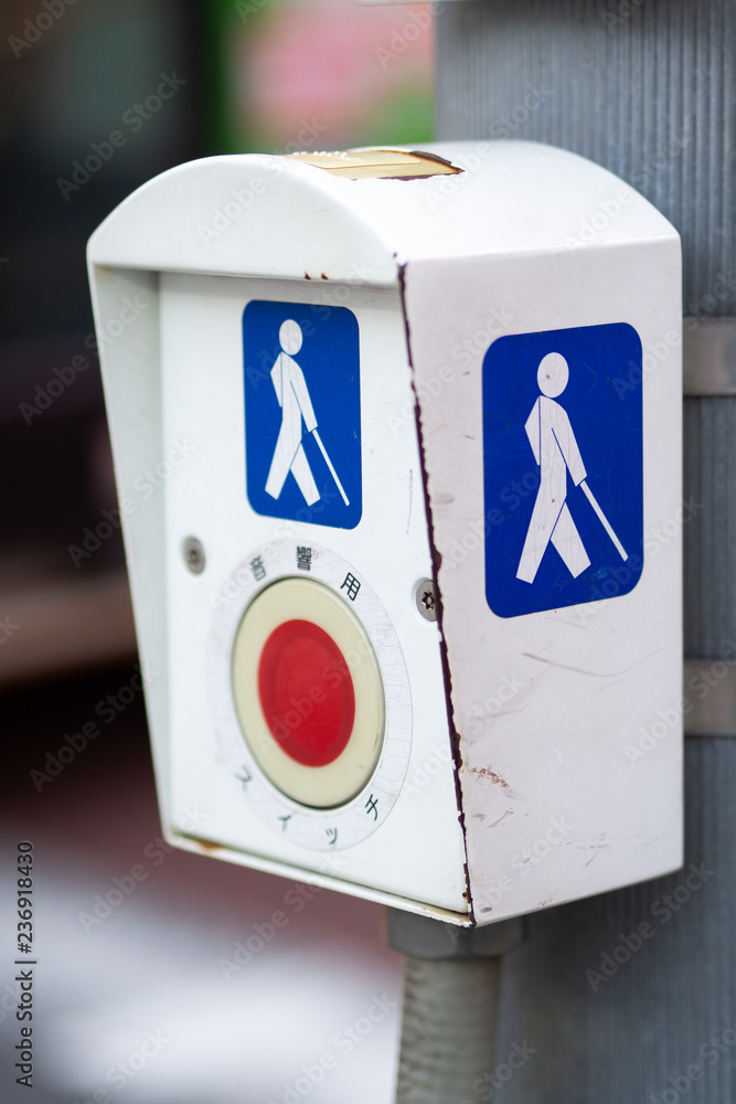 残疾人在红绿灯处过马路时按下按钮。