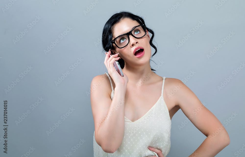 一个年轻女人在灰色背景下和她讲手机