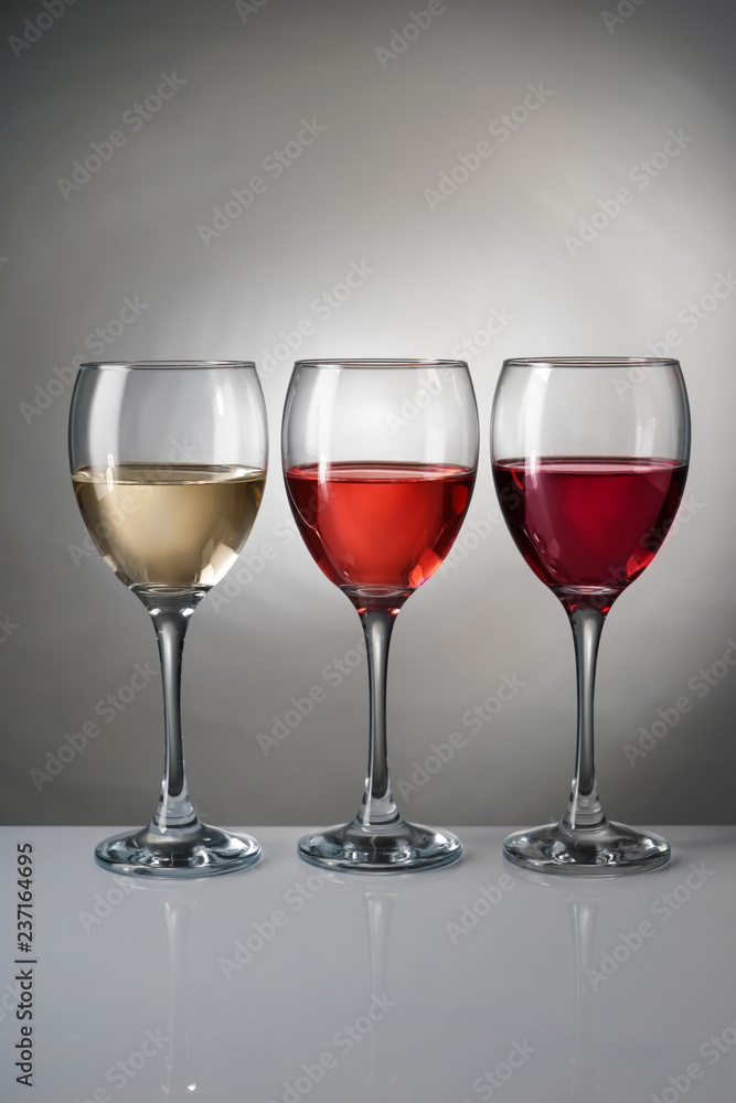 灰色背景下不同种类葡萄酒的玻璃杯