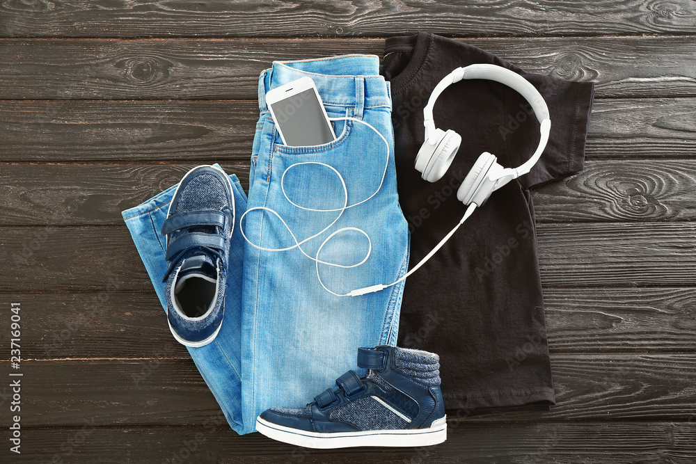 Stylish outfit with shoes and headphones on wooden background
