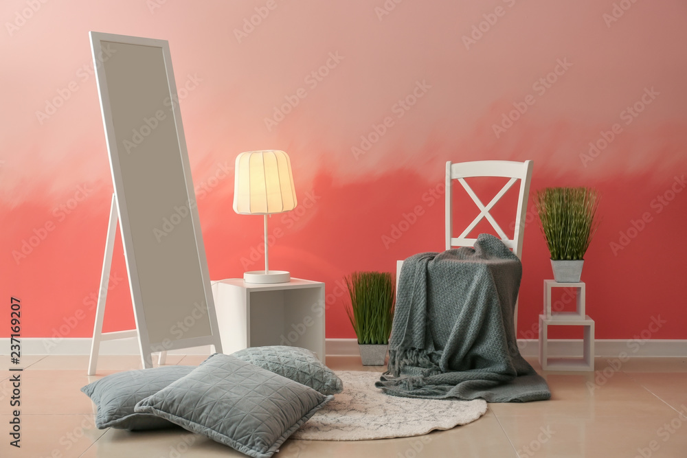 粉色墙壁附近有大镜子的舒适椅子
