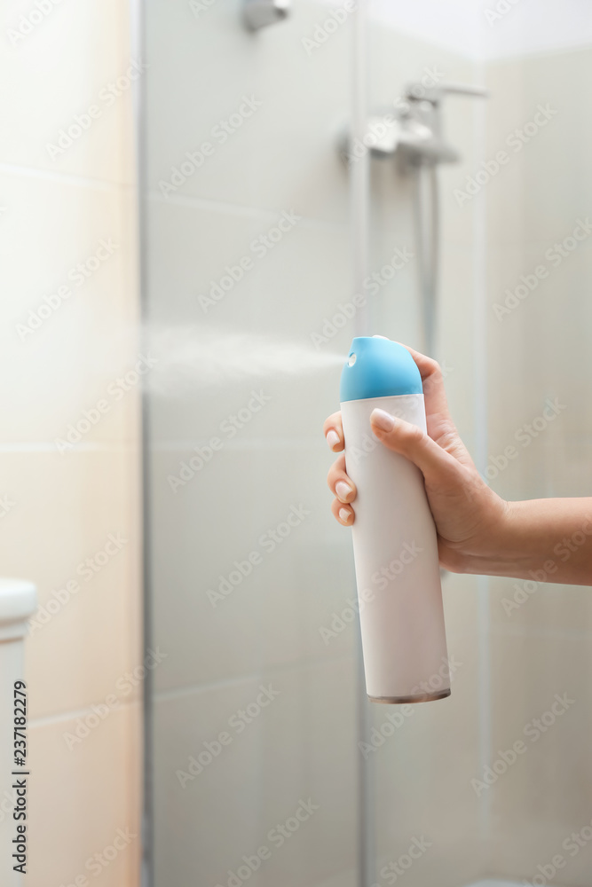 妇女在浴室喷洒空气清新剂