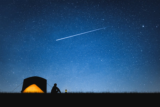 旅行者在山上和星空下露营的剪影。太空背景。