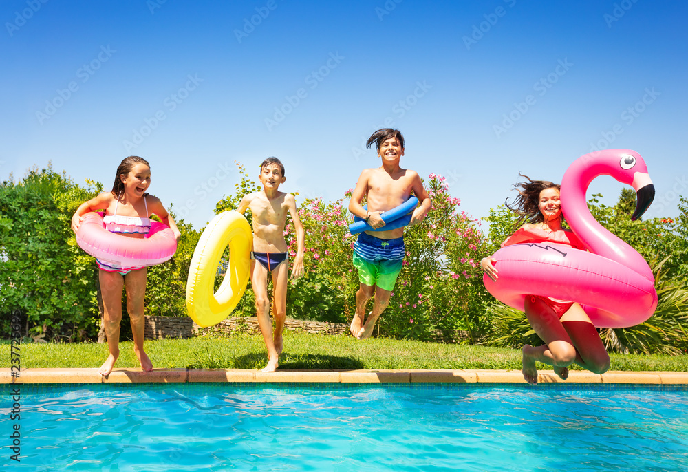 Happy teens with swim tools jumping into the pool